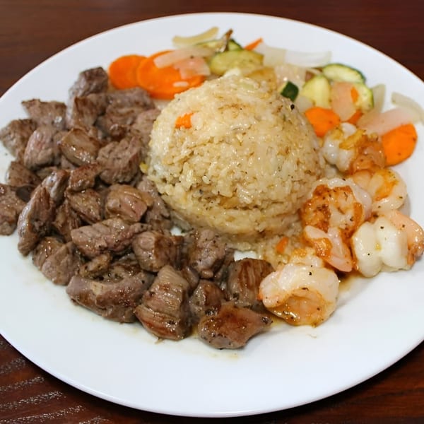 Hibachi steak, shrimp, fried rice, and mixed vegetables on a white plate.