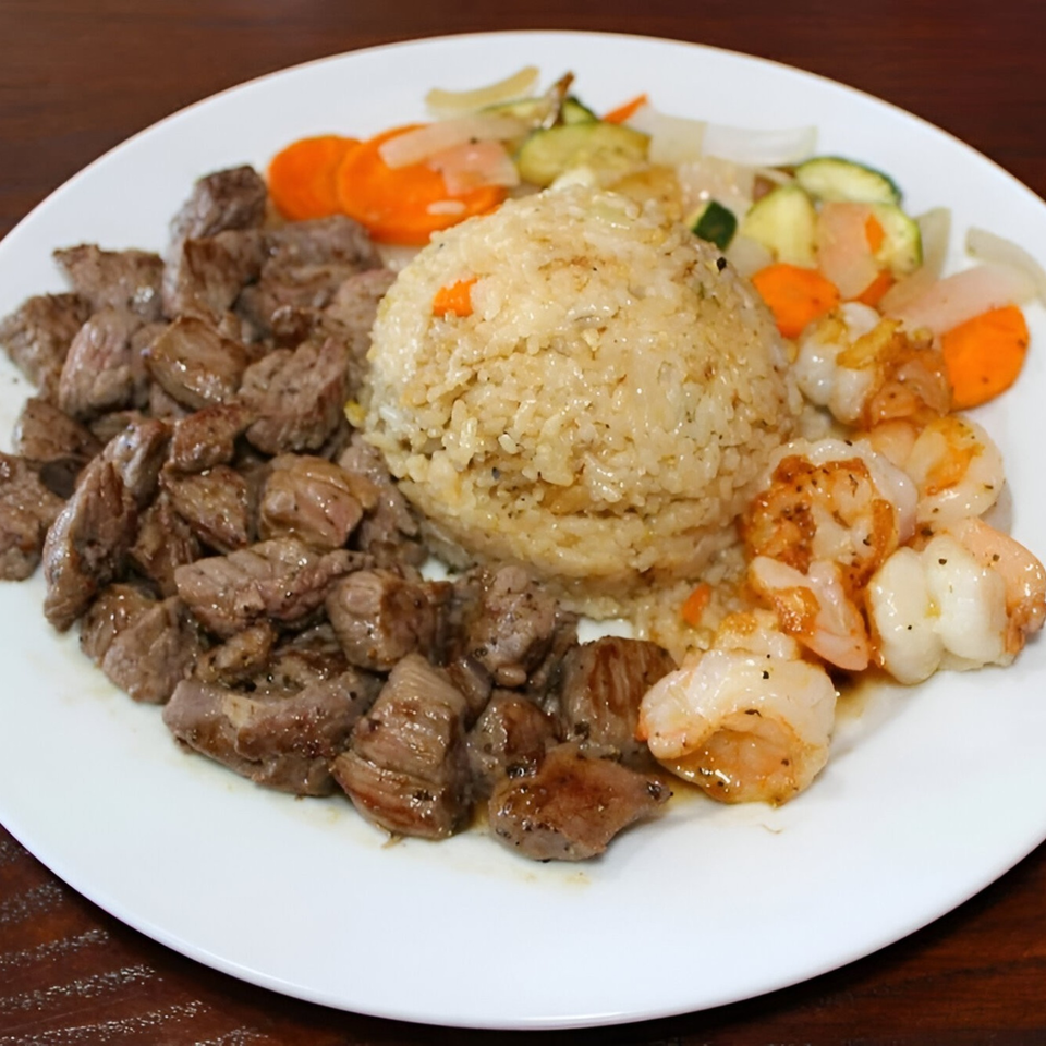 Hibachi steak, shrimp, fried rice, and mixed vegetables on a white plate.